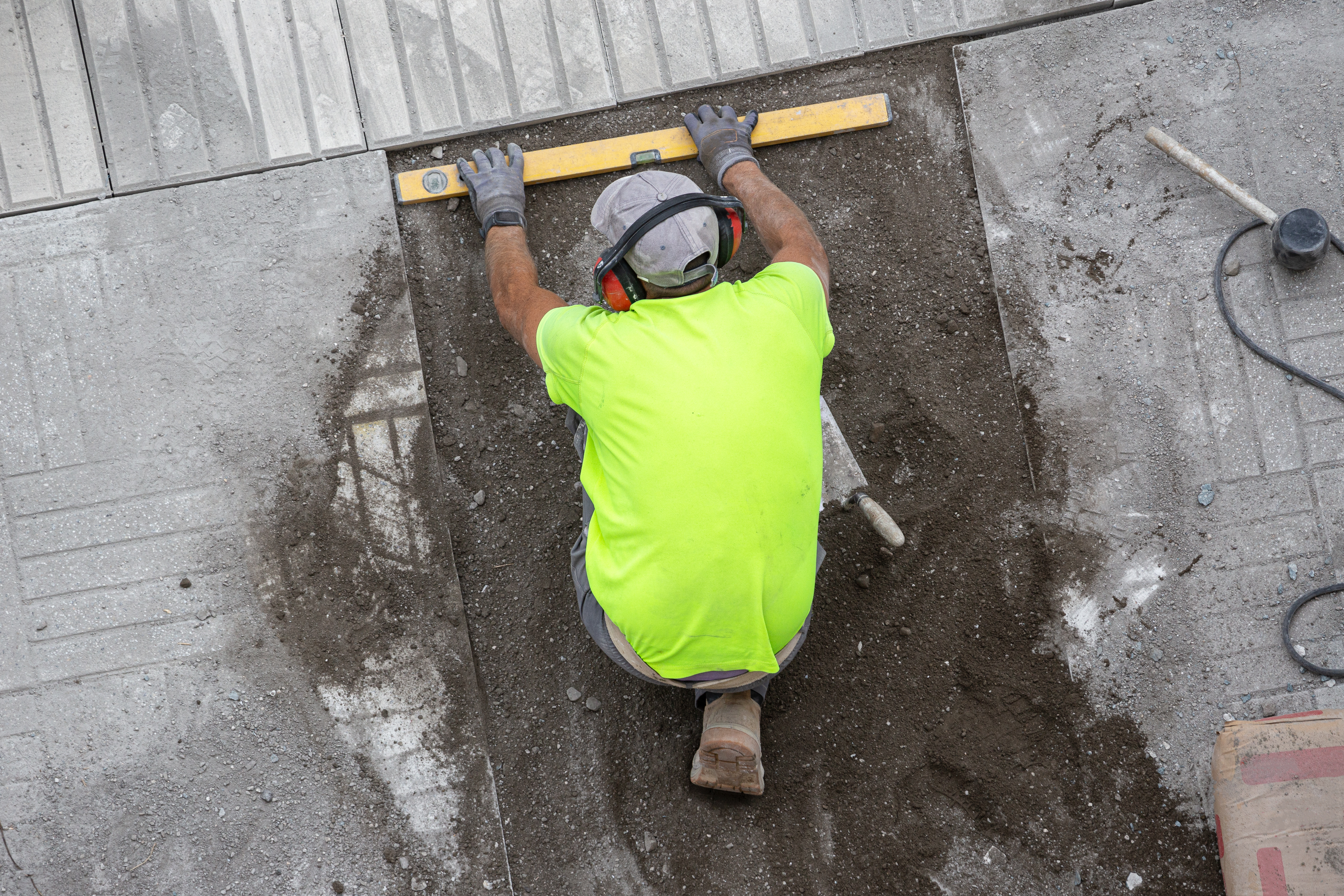 Construction worker with construction level working on a sidewalk. Maintenance concept